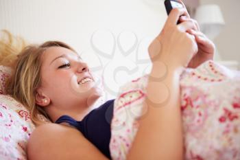 Teenage Girl Sending Text Message Whilst Lying In Bed