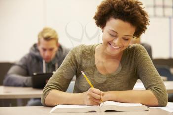 Female High School Student Studying At Desk In Classroom