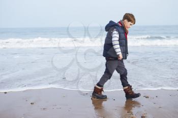 Young Boy Walking Along Winter Beach