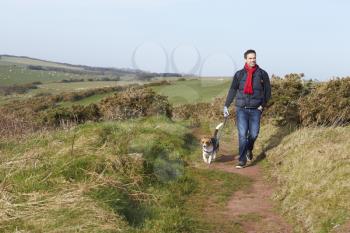 Man With Dog Walking Along Coastal Path