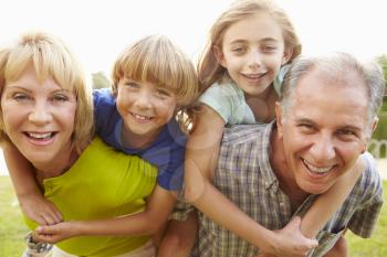 Grandparents Giving Grandchildren Piggyback Ride In Garden