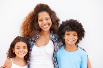 Mother And Children Standing Outdoors Against White Wall