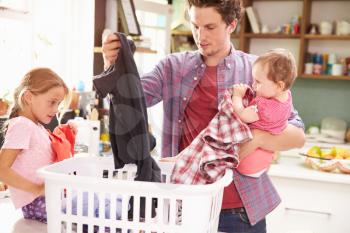 Father And Children Sorting Laundry In Kitchen