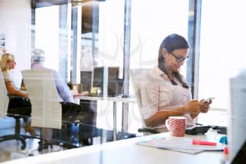 Woman using smart phone,phone at her desk in an office