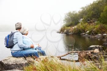 Senior couple sitting together by a lake admiring the view