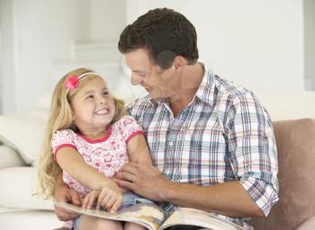 Father And Daughter Reading Book At Home