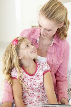 Mother And Daughter Reading Book In Bedroom