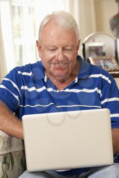Retired Senior Man Sitting On Sofa At Home Using Laptop