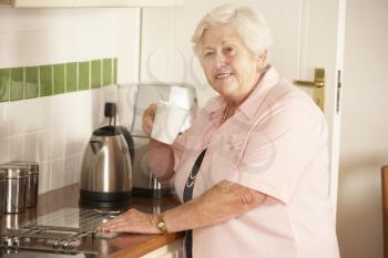Retired Senior Woman In Kitchen Making Hot Drink