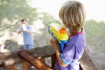 Father And Son Having Water Pistol Fight In Tree House