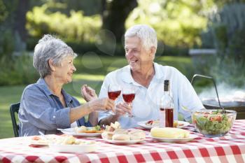 Senior Couple Enjoying Barbeque In Garden Together