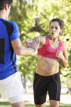 Young Woman Working With Personal Trainer In Park