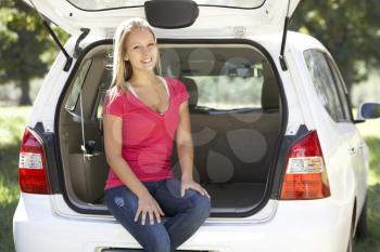 Young Woman Sitting In Trunk Of Car