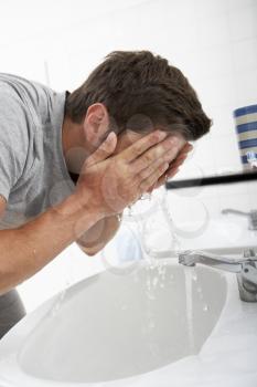 Man Washing Face In Bathroom Sink