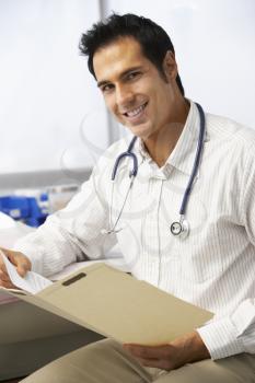 Male Doctor In Surgery Reading Patient Notes