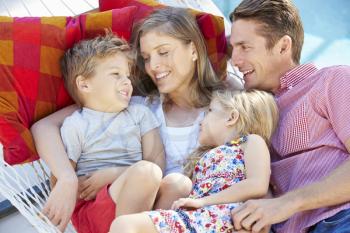 Family Relaxing In Garden Hammock Together