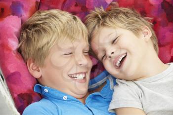 Two Young Boys Relaxing In Garden Hammock Together