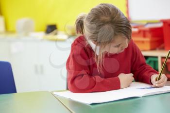 Female Pupil Practising Writing At Table