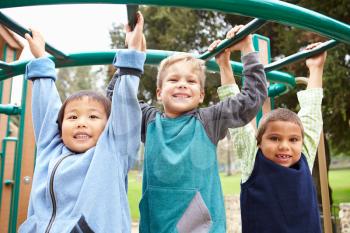 Three Young Boys On Climbing Frame In Playground