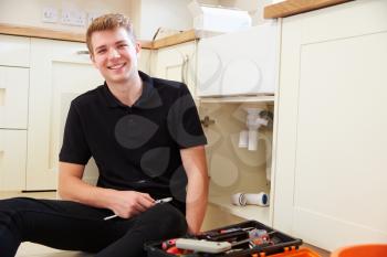 Apprentice plumber sitting in a kitchen, portrait