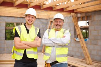 Portrait Of Carpenter With Apprentice Working On Site
