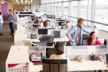 Casually dressed colleagues talking in an open plan office