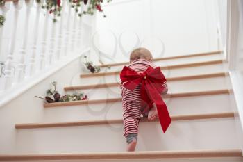 Toddler With Christmas Bow On Stairs In Pajamas