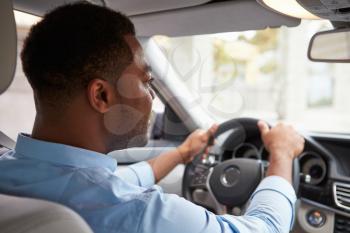 In car view of young male African American driver with coffee