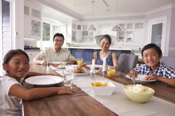 Portrait Of Family Eating Meal At Home Together