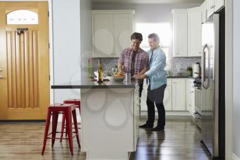 Male couple in the kitchen preparing a meal, looking down