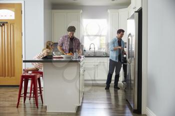 Daughter in kitchen watches her male parents prepare meal