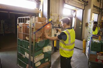 Man in a warehouse holds and scans a box for delivery