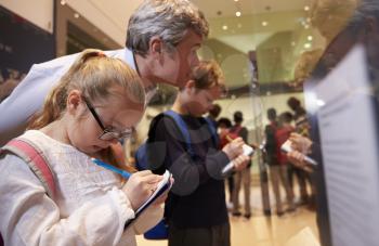 Teacher And Pupils Looking At Artifacts On Display In Museum