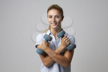 Studio Portrait Of Female Sports Coach Holding Weights