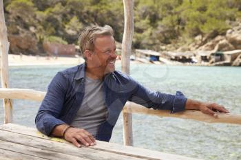 Middle aged Caucasian man sitting at a table on a jetty