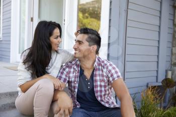 Affectionate Couple Sitting On Steps Outside Home