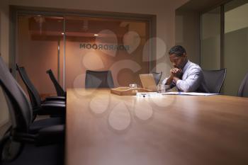 Middle aged black businessman works on laptop late in office
