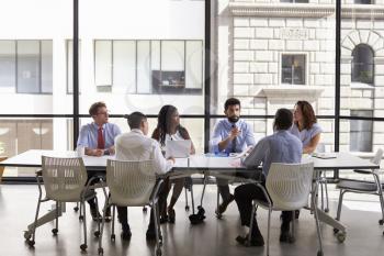 Business team look to manager at meeting in open plan office