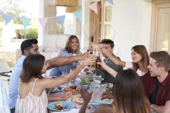 Friends making a toast at a dinner party on a patio, Ibiza
