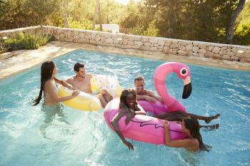 Group Of Friends On Vacation Relaxing In Outdoor Pool