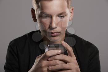 Teenage boy using mobile phone, head and shoulders, crop