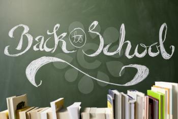 Back to school written on chalkboard, books in foreground