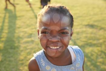 African elementary school girl smiling to camera outdoors