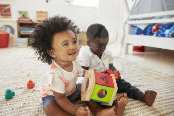 Baby Boy And Girl Playing With Toys In Playroom Together