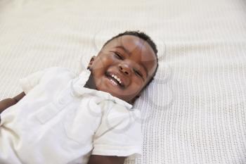 Overhead Shot Of Smiling Young Boy Lying On Bed