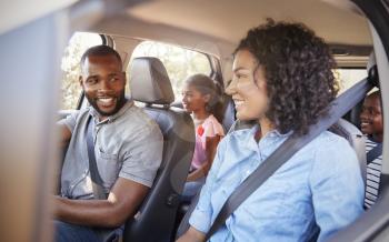 Young black family in a car on a road trip smiling