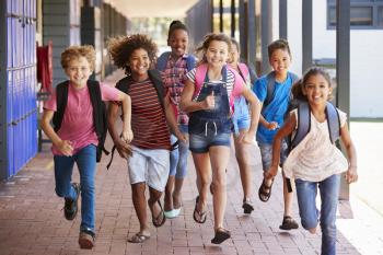 School kids running in elementary school hallway, front view