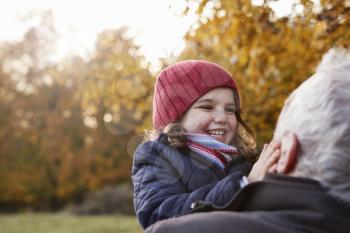 Grandfather Cuddling Granddaughter On Autumn Walk