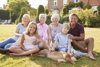 Multi generation family sitting on grass in the garden