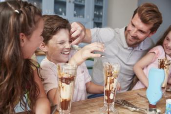 Father Making Ice Cream Sundaes With Children At Home